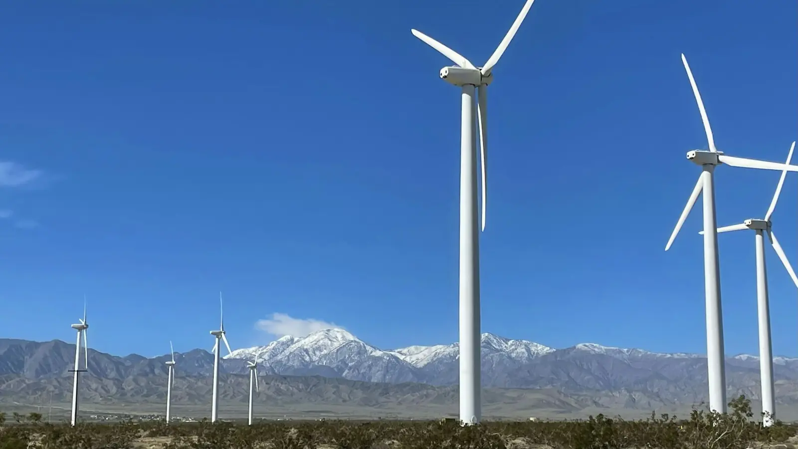 renewable energy installation — a bunch of windmills in the desert with mountains in the background